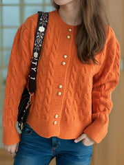 Orange cable knit cardigan with puff sleeves and gold buttons.