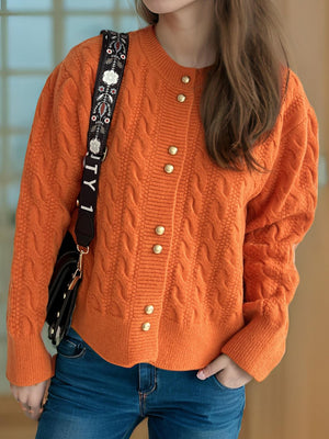 Orange cable knit cardigan with puff sleeves and gold buttons.
