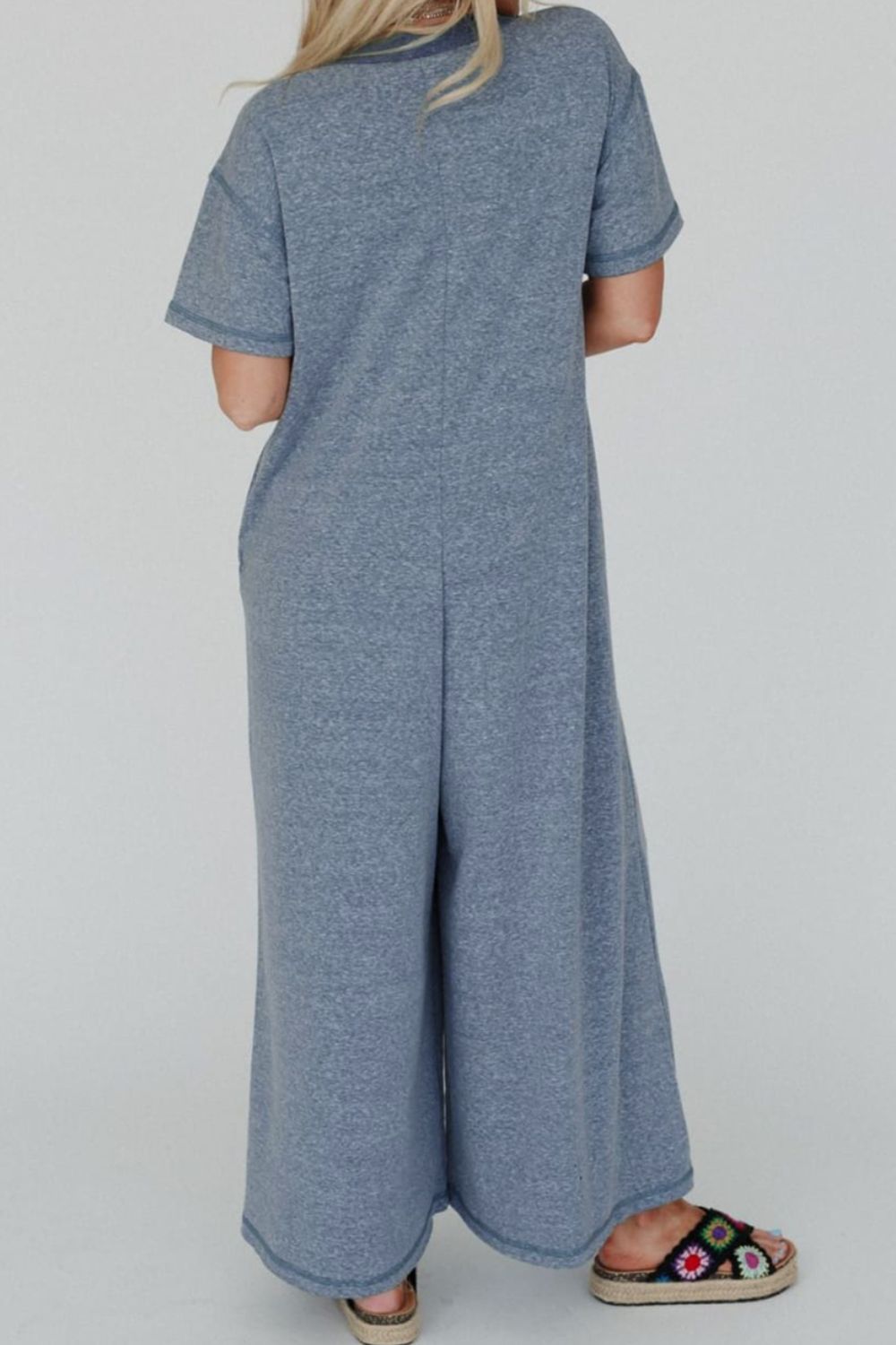 Denim-trimmed wide-leg utility jumpsuit in dusty blue with short sleeves and a relaxed fit.