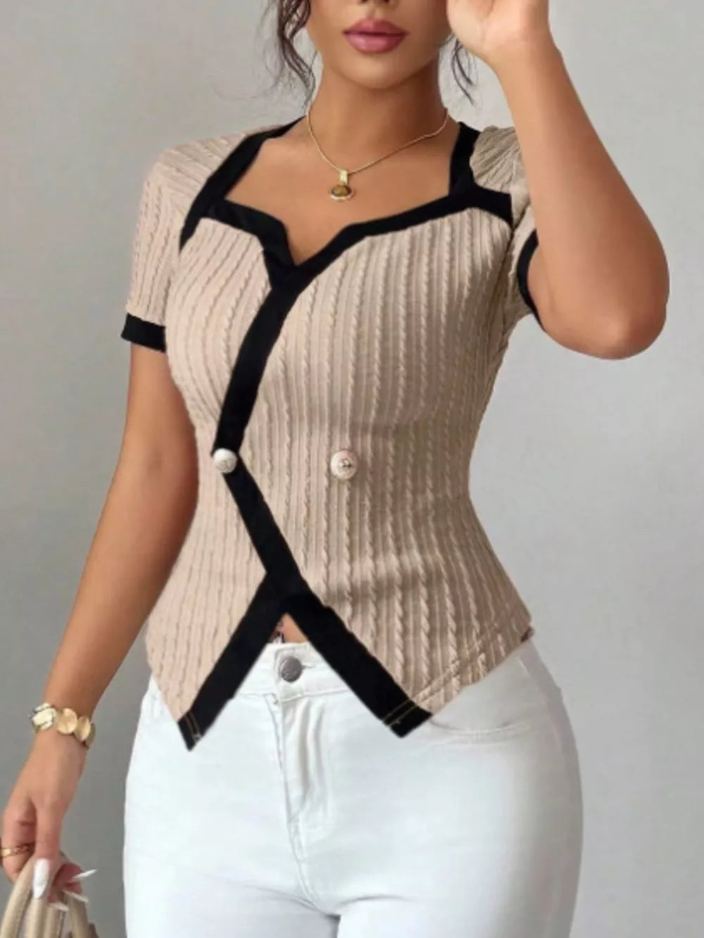 Beige knit t-shirt with asymmetrical black contrast trim and buttons.