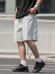 Men's light gray textured drawstring shorts with elastic waistband and pockets.