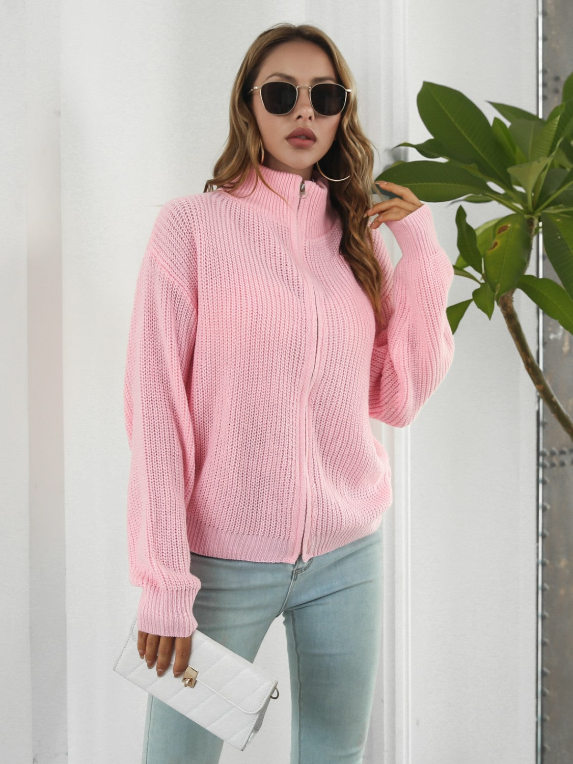 Blush pink ribbed knit zip-up sweater with a mock neck and full zip closure.