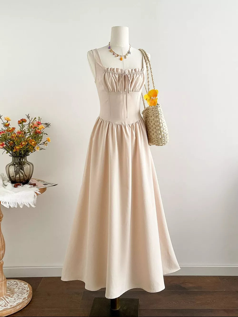 Elegant square neck A-line maxi dress in beige with tie detail and gathered bodice.