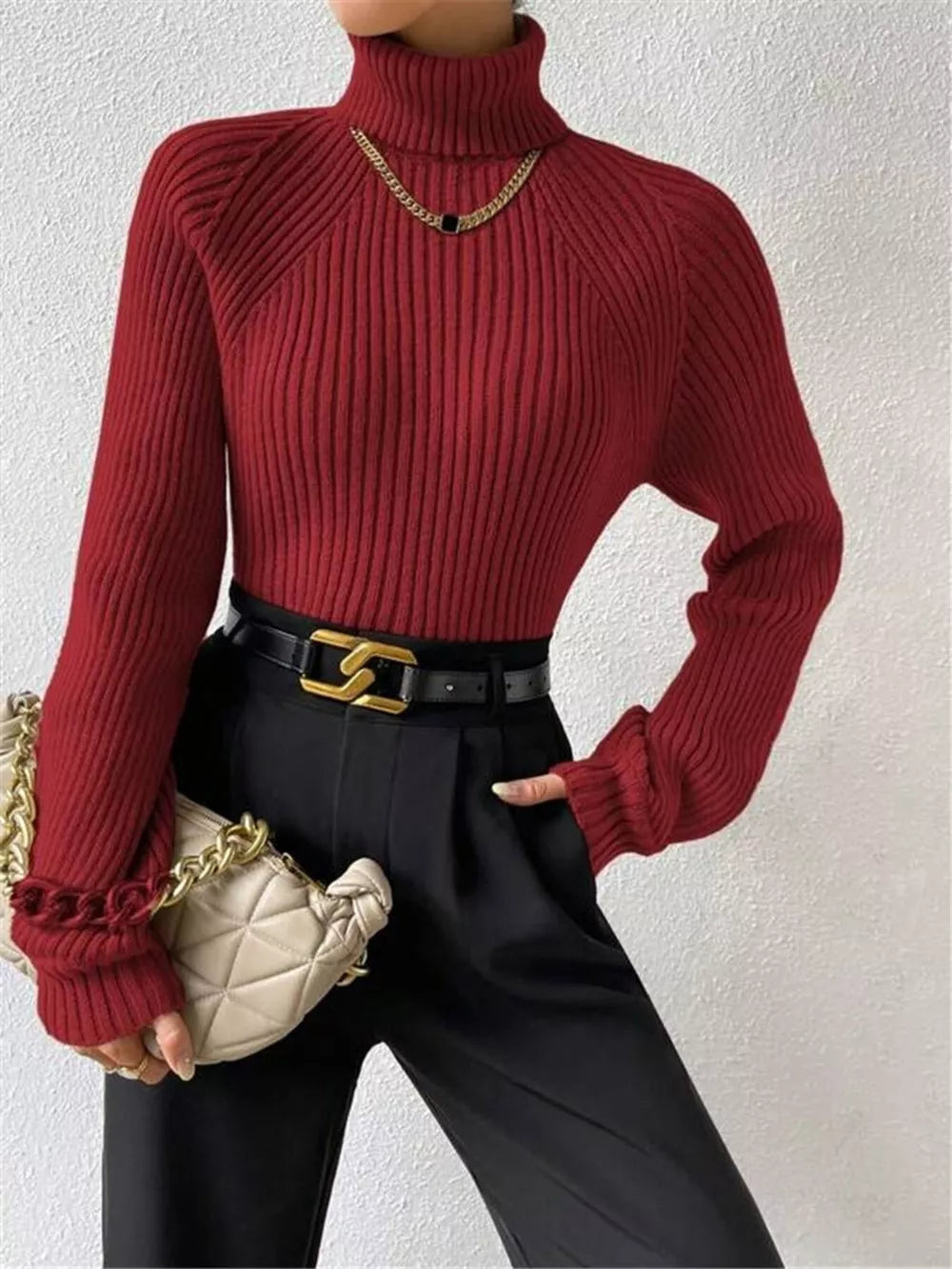 Burgundy ribbed turtleneck sweater with ruffled cuffs and gold chain necklace.