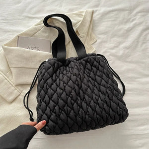 Black quilted drawstring carryall bag with dual straps and a casual trapezoid shape.
