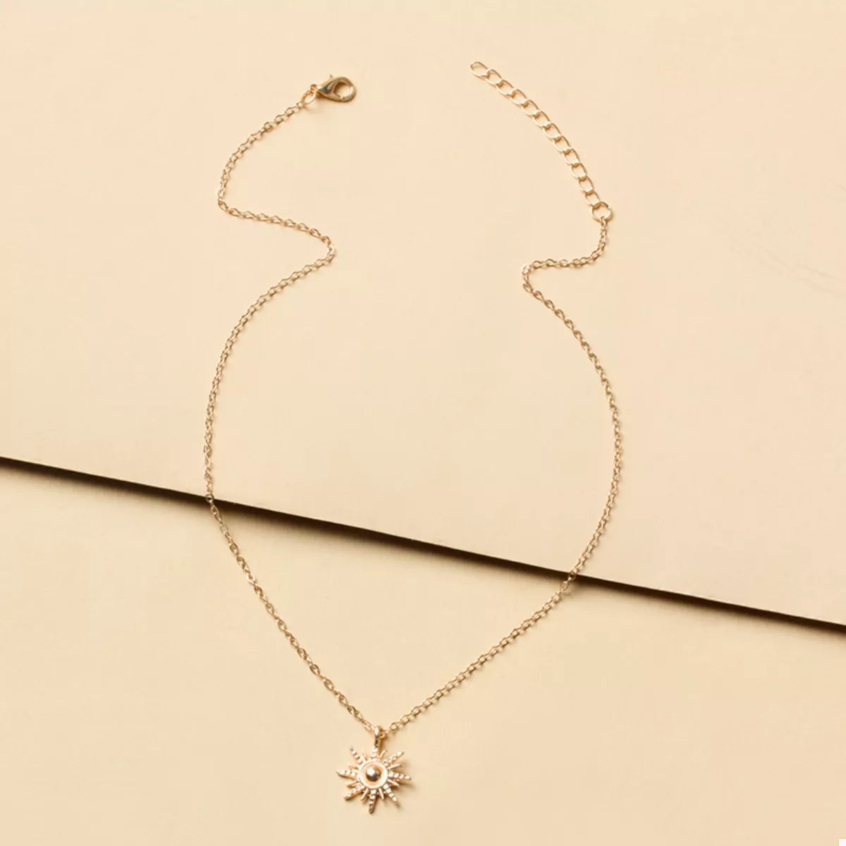 Gold sunburst pendant necklace with delicate chain and lace trim detail.