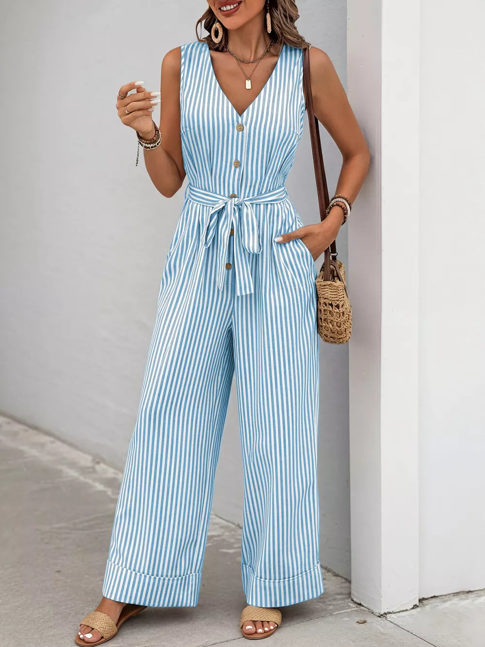 Light blue striped tie-waist wide leg romper with decorative buttons and pockets.