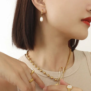 Gold hoop earrings with lustrous pearl drop, styled with a gold beaded necklace.