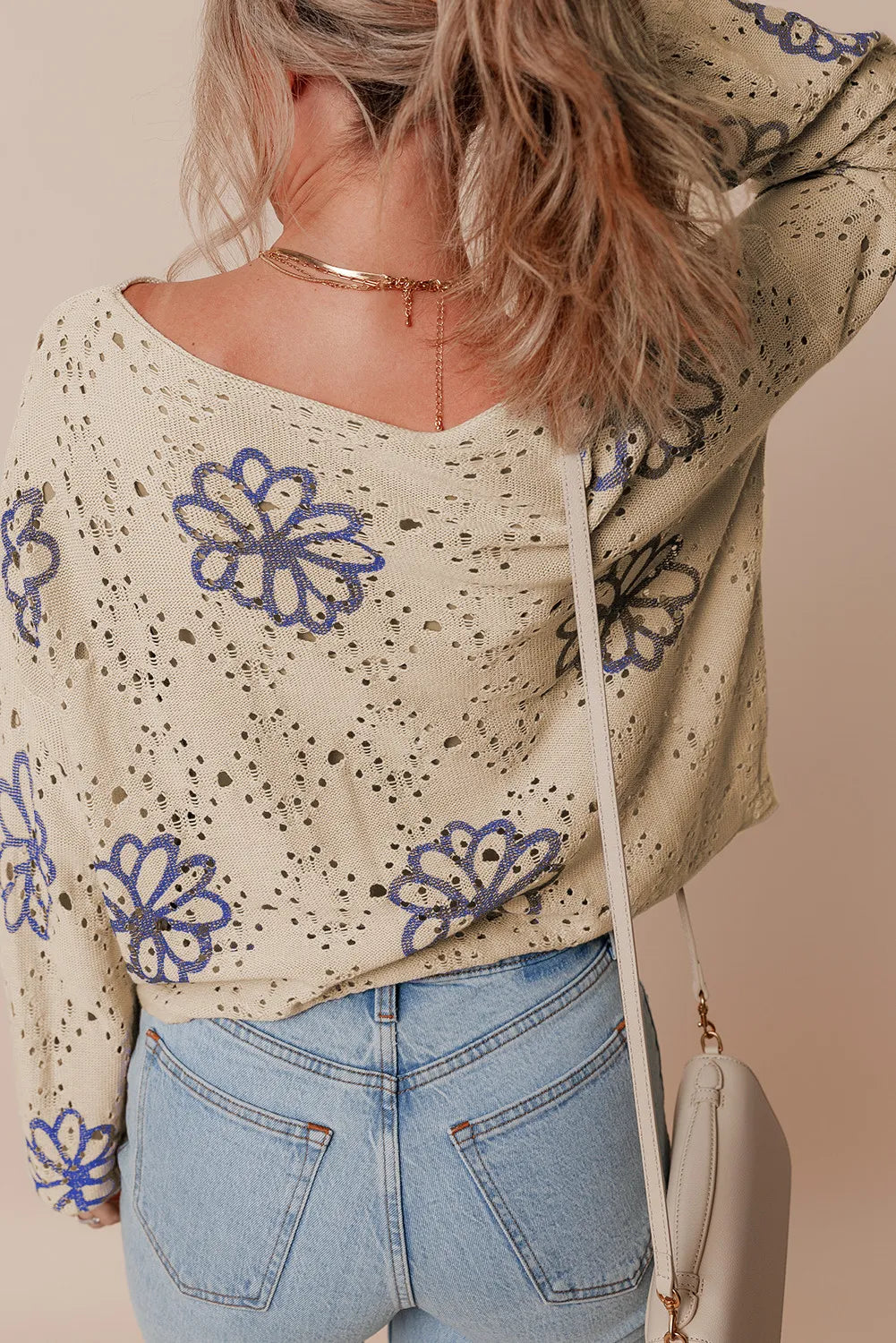 Beige eyelet knit pullover with blue floral embroidery and a V-neck.