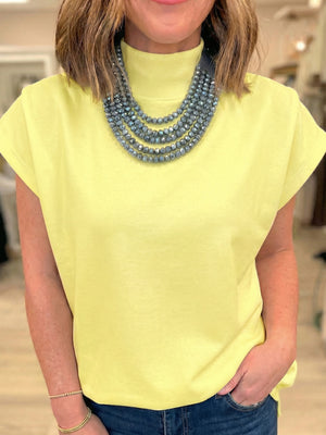Yellow mock neck cap sleeve t-shirt with layered beaded necklace
