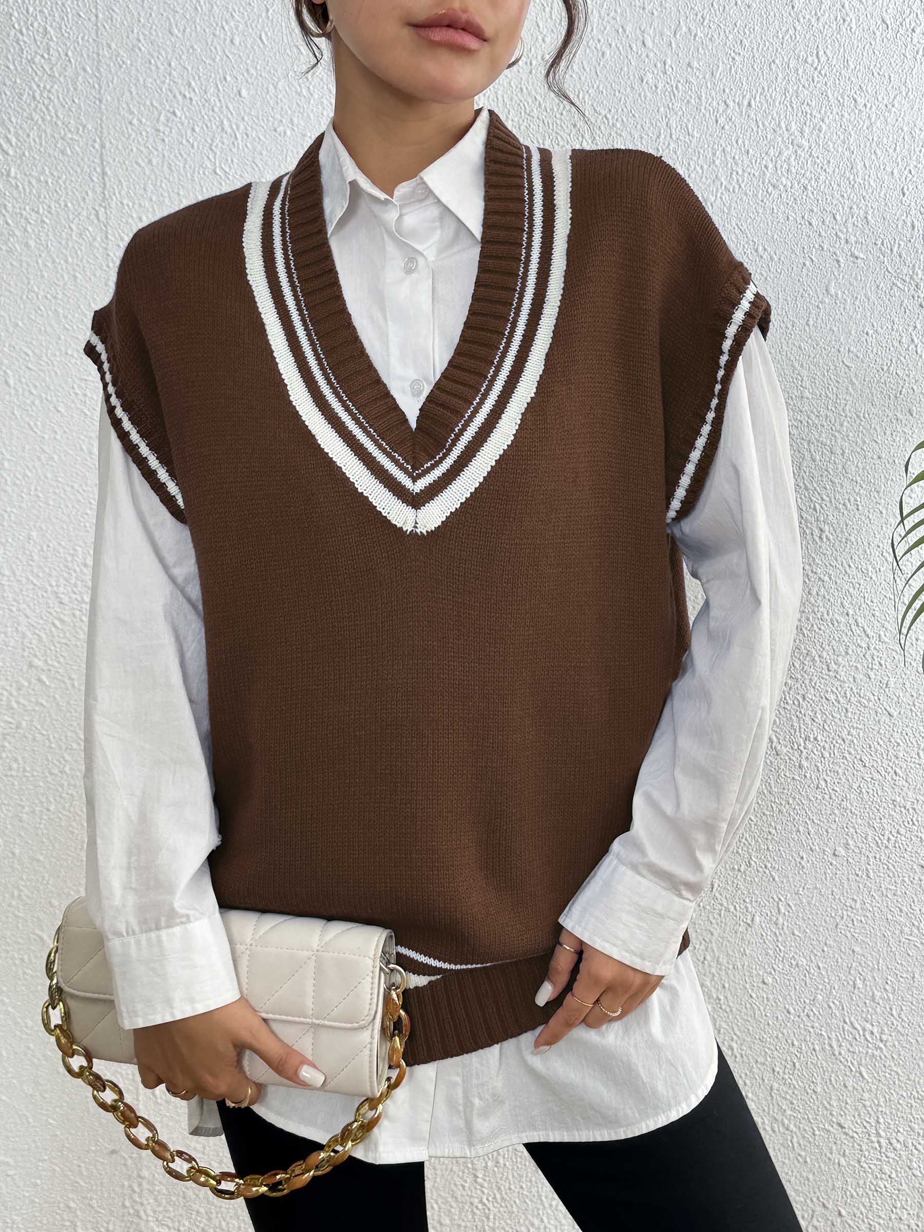 Brown acrylic knit vest with white contrast trim and V-neck, styled with a white shirt.
