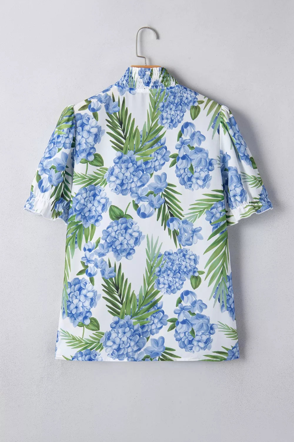 White short sleeve blouse with blue hydrangea floral print and smocked collar.