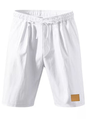 White chino shorts with drawstring waist and faux leather patch detail.