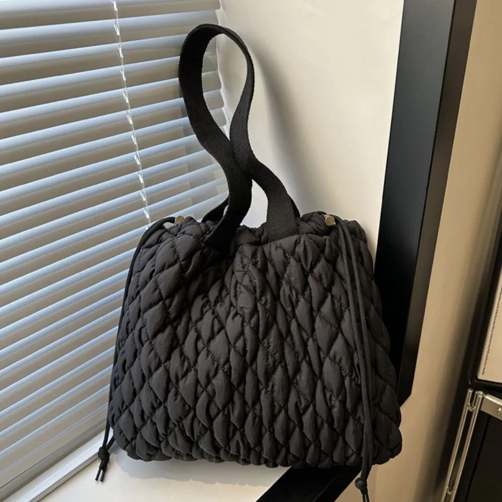 Black quilted drawstring carryall bag with diamond pattern and dual handles.