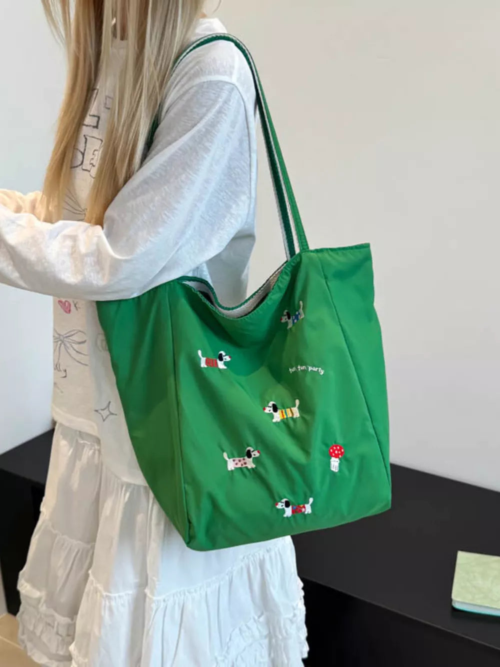 Green shoulder bag with embroidered dachshunds and mushrooms, featuring dual straps.