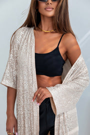 Beige sequin kimono jacket with wide sleeves, worn open over a black camisole.