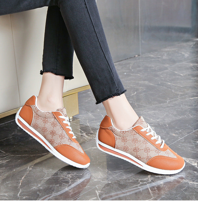 Lace-up round toe sneakers in tan with brown logo pattern and orange accents.