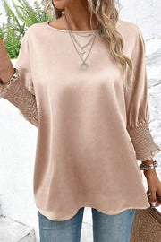 Satin batwing blouse in a neutral tone with shirred cuffs and a round neckline.