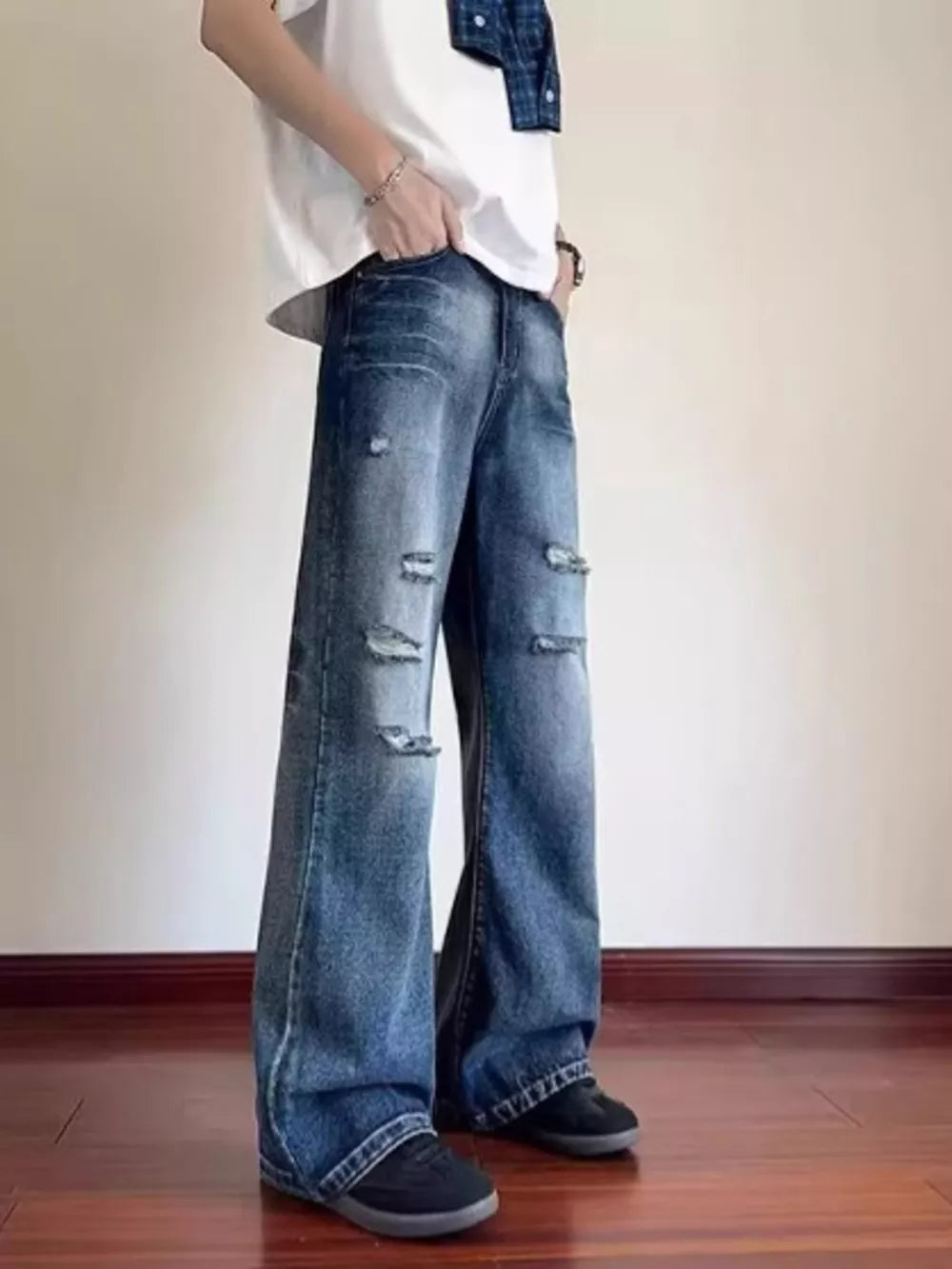 Distressed wide-leg blue denim jeans with pockets and ankle pooling.