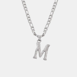 Silver initial pendant necklace with textured letter M on a figaro chain.