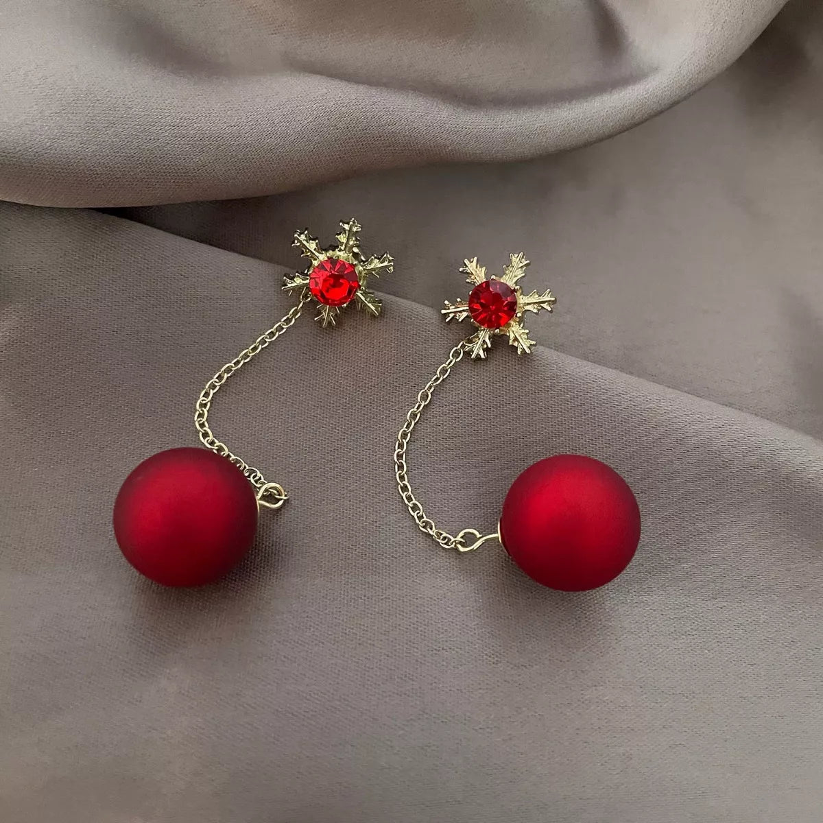 Deep red snowflake drop earrings with gold chain and red ball accent