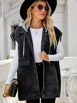 Dark denim utility vest with hood and pockets, open front, worn by a woman.