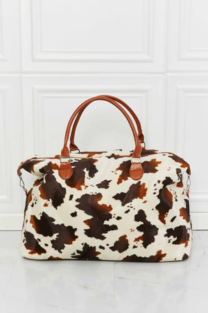 Brown and white cowhide print duffel bag with leather handles