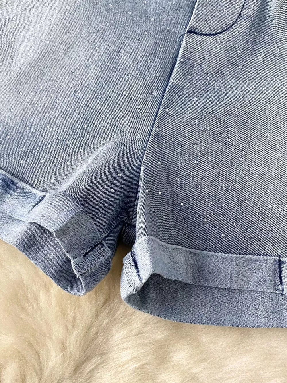 Blue denim romper with rhinestone embellishments and cuffed hems.