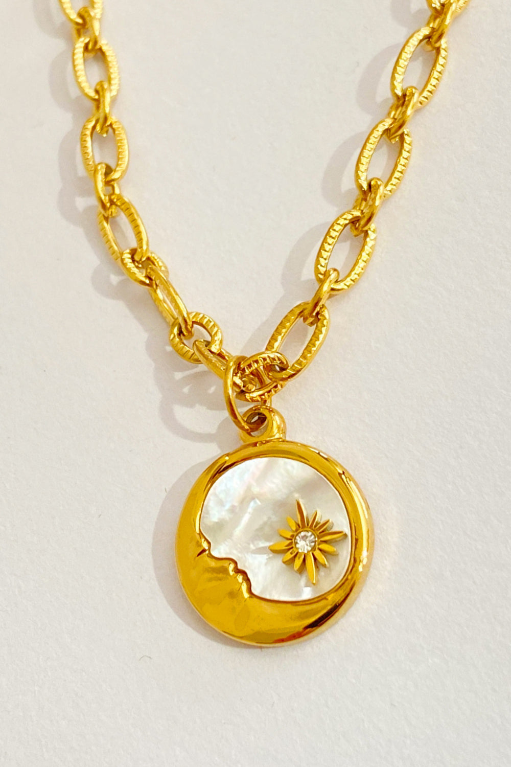 18K gold-plated celestial charm necklace with moon and star detail on mother of pearl inlay.