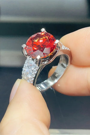 Crimson solitaire ring with pave band in silver, featuring a large faceted red stone.