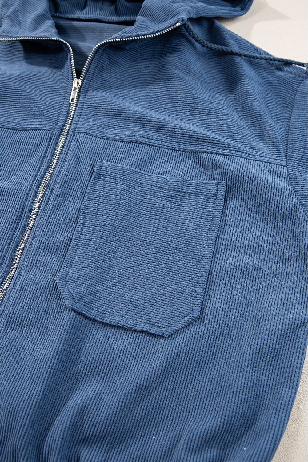 Dusty blue corduroy bomber hoodie with zipper and chest pocket.