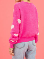 Fuchsia pink crewneck sweater with white intarsia hearts on sleeves and body.