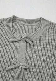 Gray ribbed knit cardigan with tie-front detail and bow accents.
