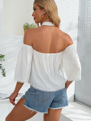 White off-the-shoulder blouse with lace trim and short sleeves, styled with denim shorts.