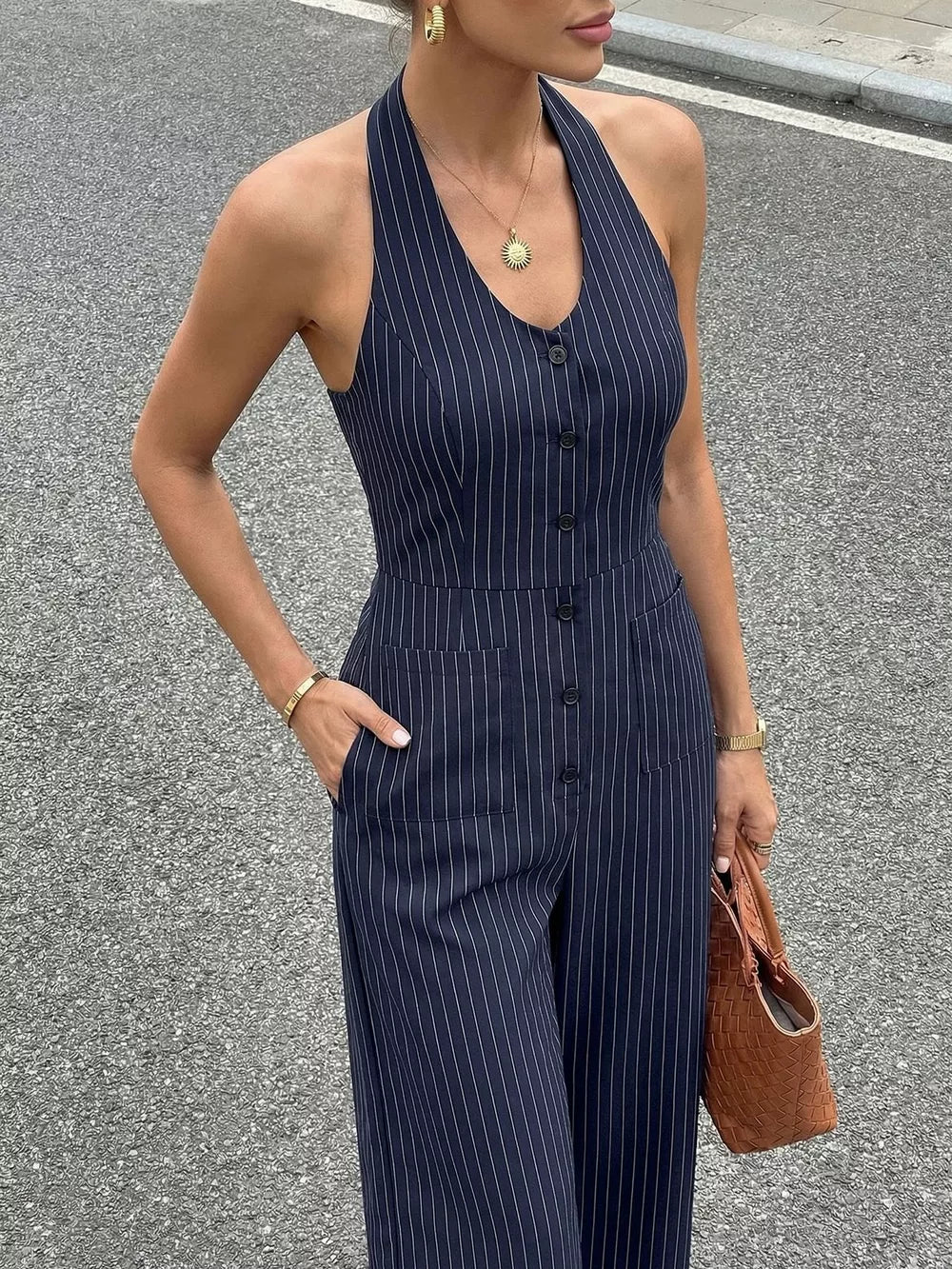 Navy pinstripe halter jumpsuit with decorative buttons and pockets.