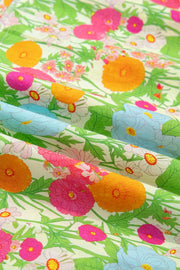 Vibrant floral maxi dress fabric with ruffled neckline detail, featuring orange, pink, blue, and white flowers on a light