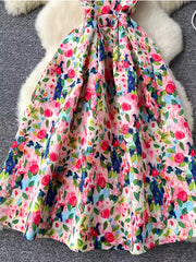 Vibrant floral midi dress with pleated skirt in pink and yellow, featuring a colorful abstract floral print.