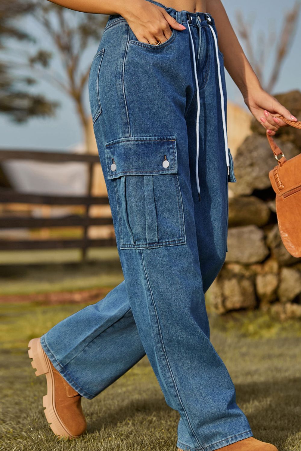 Medium wash denim cargo pants with drawstring waist and pleated cargo pockets.