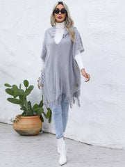 Textured knit poncho in dark gray with fringe and wooden buttons, styled with a turtleneck.
