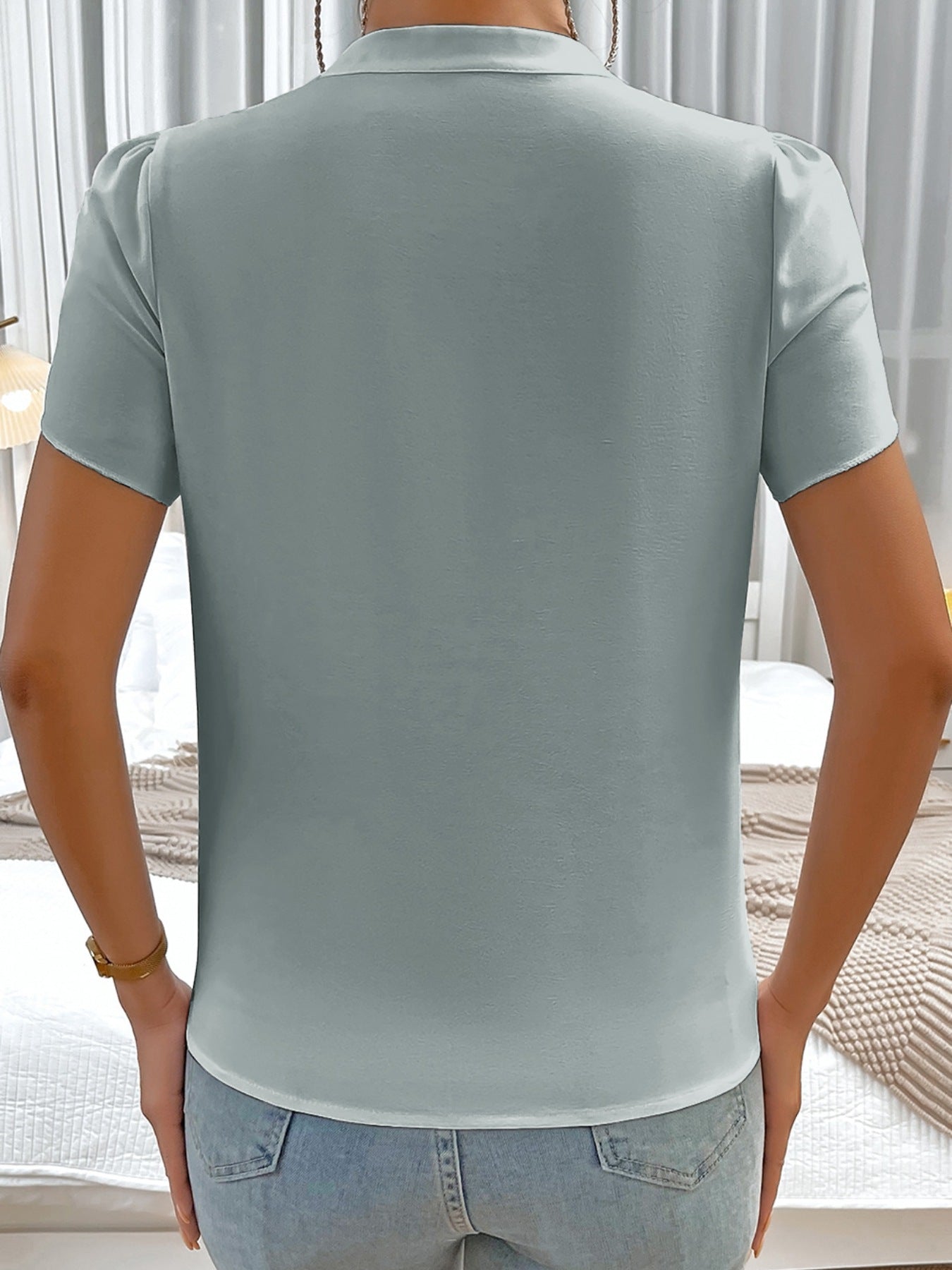 Light blue blouse with notched neckline and petal sleeves, buttoned back detail.