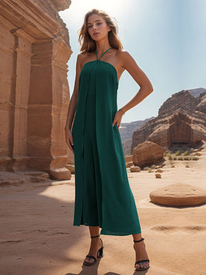 Dark green draped halter jumpsuit with palazzo legs and front slit detail.