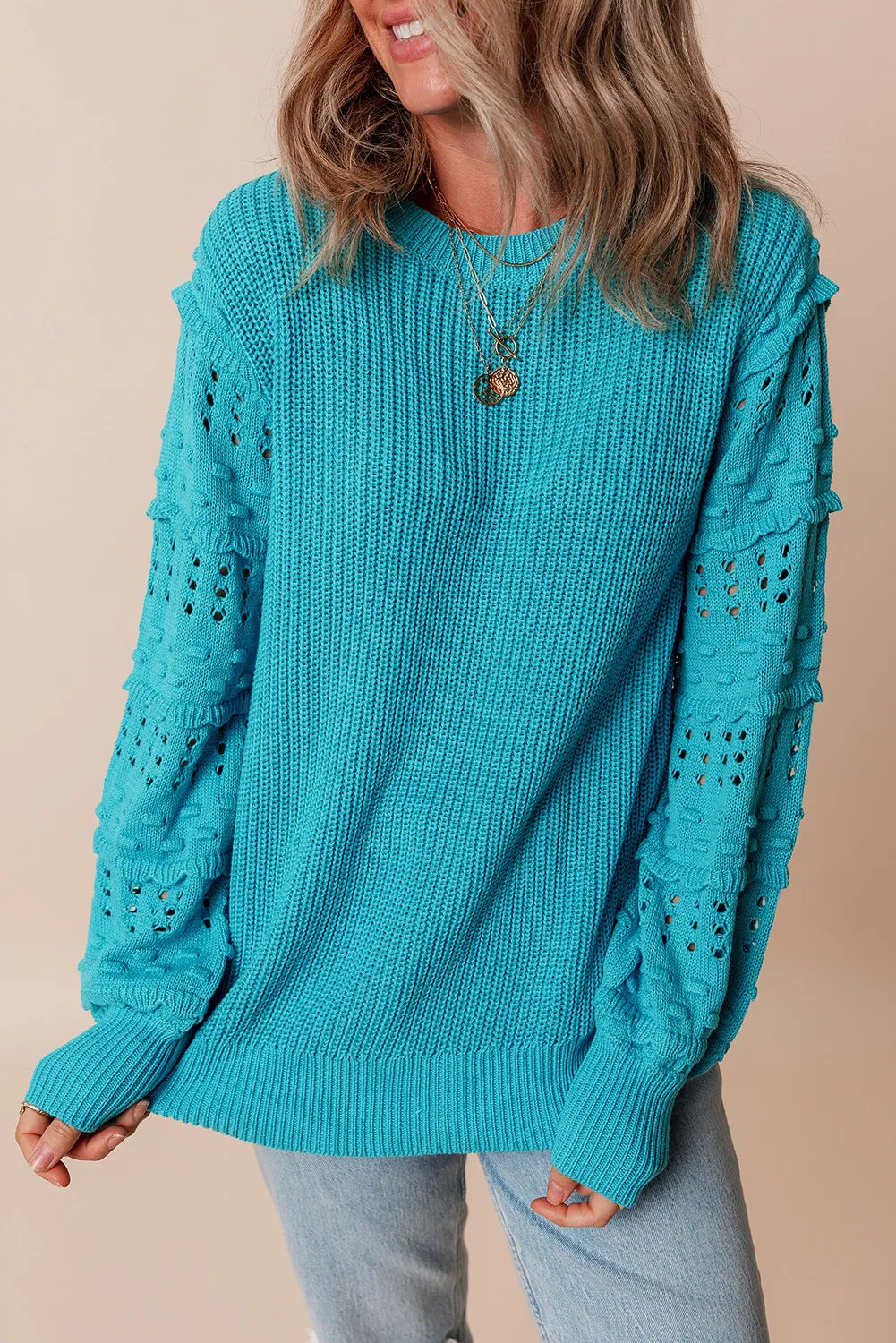 Turquoise knit sweater with textured cutout sleeves and crew neck.