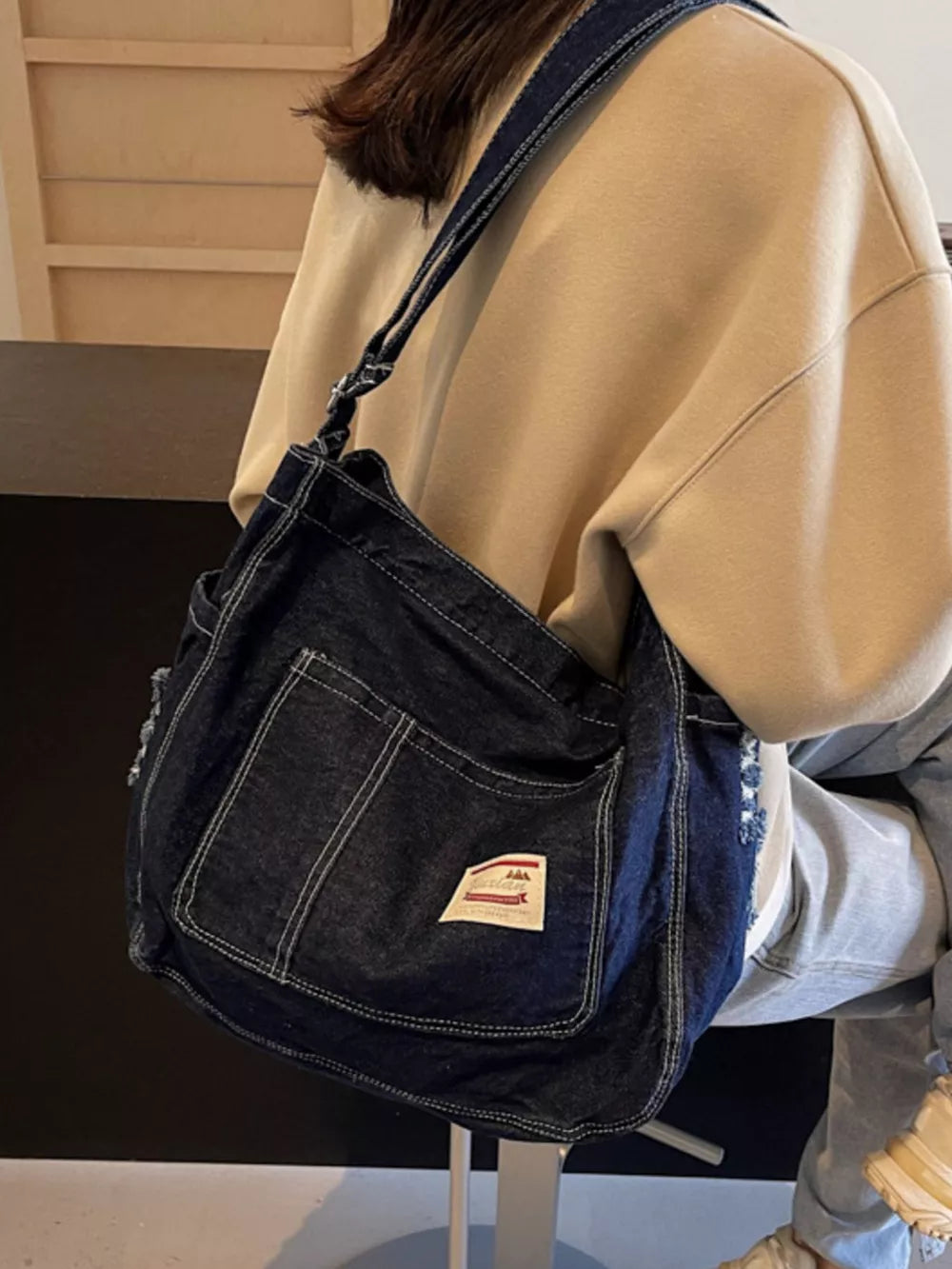 Slouchy dark blue denim crossbody bag with contrast stitching and adjustable strap.