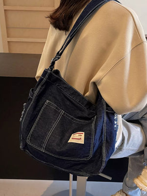 Slouchy dark blue denim crossbody bag with contrast stitching and adjustable strap.