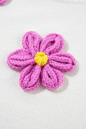 White knit sweater with a pink embroidered flower detail and yellow center.