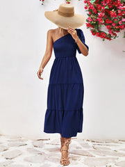 Dark blue smocked bodice tiered one-shoulder dress with a puff sleeve.
