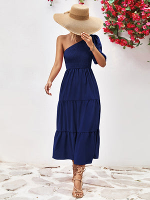 Dark blue smocked bodice tiered one-shoulder dress with a puff sleeve.