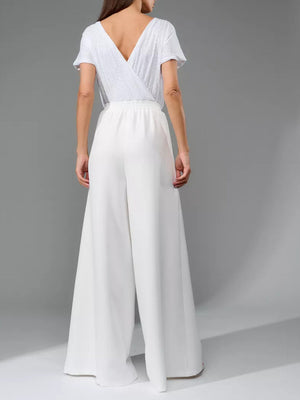 White sequin wrap bodice with short sleeves and white palazzo pants.