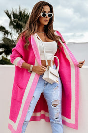 Color-blocked hooded knit maxi cardigan in hot pink with white stripes, featuring pockets and a relaxed fit.