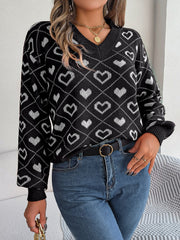 Black acrylic V-neck sweater with allover white heart jacquard pattern and ribbed cuffs.